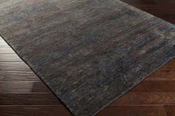 Close-up of the textured Wyano Jute Carpet on dark wood floor. Contemporary style rug in shades of blue and brown. Corner