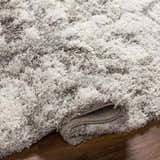 Close-up of the plush Wynant Gray Tones Rug, showing its soft texture, light gray, medium gray, and off-white colors. Fold