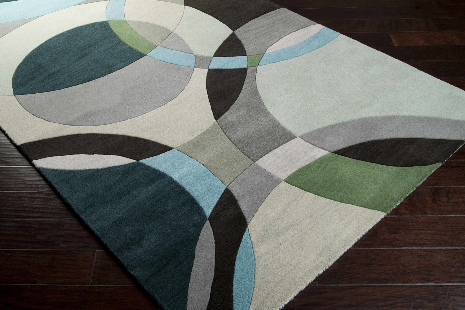 Close-up of the hand-tufted Wyocena Wool Rug. Contemporary design with aqua, black, gray, and green circles. Corner