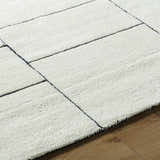 Close-up of the hand-tufted Xylia Ivory Area Rug. Pearl wool rug with a contemporary geometric block pattern. Texture