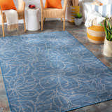 Coastal patio scene with blue Yackandandah Flatweave Area Carpet, wicker chairs, and bright orange pillows. Roomscene-Rectangle