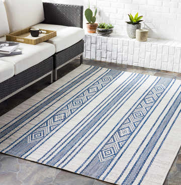 Living room scene with a white sofa and the blue striped Yankalilla Area Rug on a stone floor. Roomscene-Rectangle