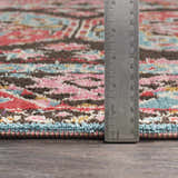 Close-up of the Yettem Clearance Rug showing aqua, brown, pink, and red tones. Ruler shows rug pile height. Pile