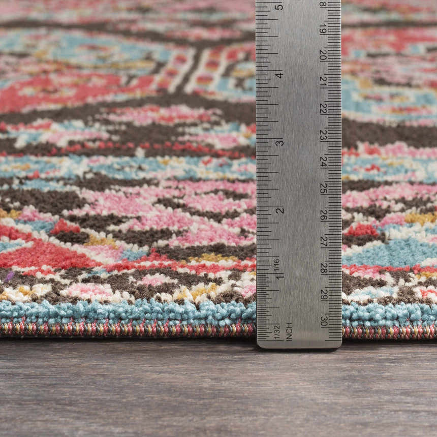 Close-up of the Yettem Clearance Rug showing aqua, brown, pink, and red tones. Ruler shows rug pile height. Pile
