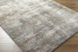 Close-up of the Yoshe Thick Luxe Rug. Beige, gray, and tan tones with a contemporary abstract pattern. Soft, plush texture. Corner