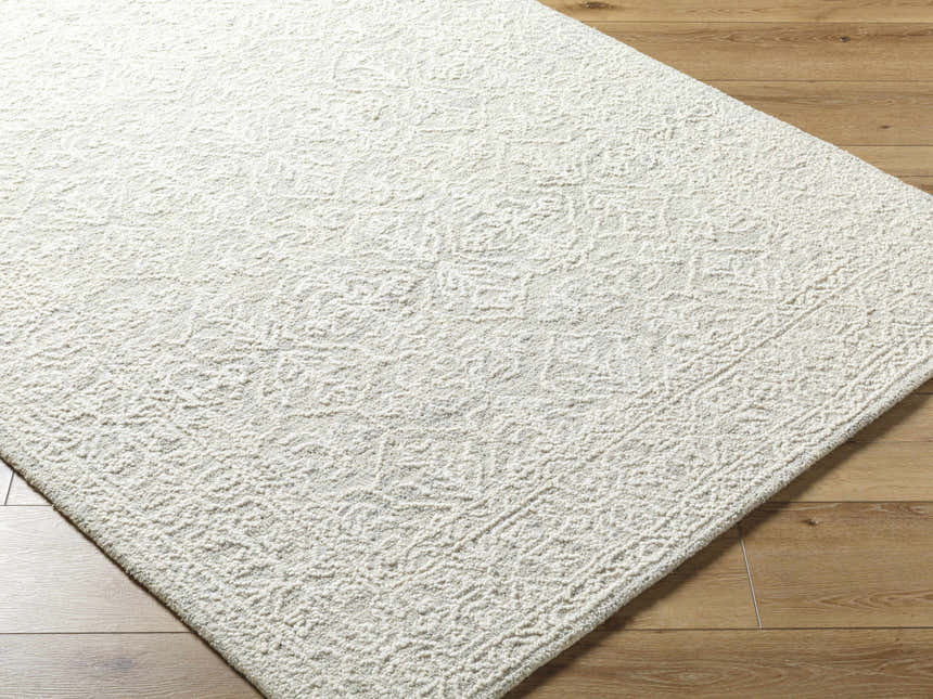 Close-up of the hand-tufted Yadid Sage Wool Area Rug, showing its subtle traditional pattern and soft, textured wool pile. Corner