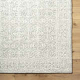 Close-up of the hand-tufted Yadid Gray Wool Area Rug featuring a traditional light silver and gray floral pattern. Corner