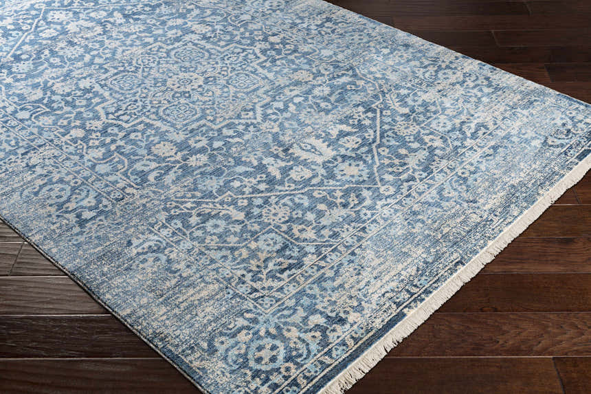 Close-up of the Yorkana Distressed Blue Rug showing its traditional, vintage pattern and soft blue, beige, and gray colors. Corner