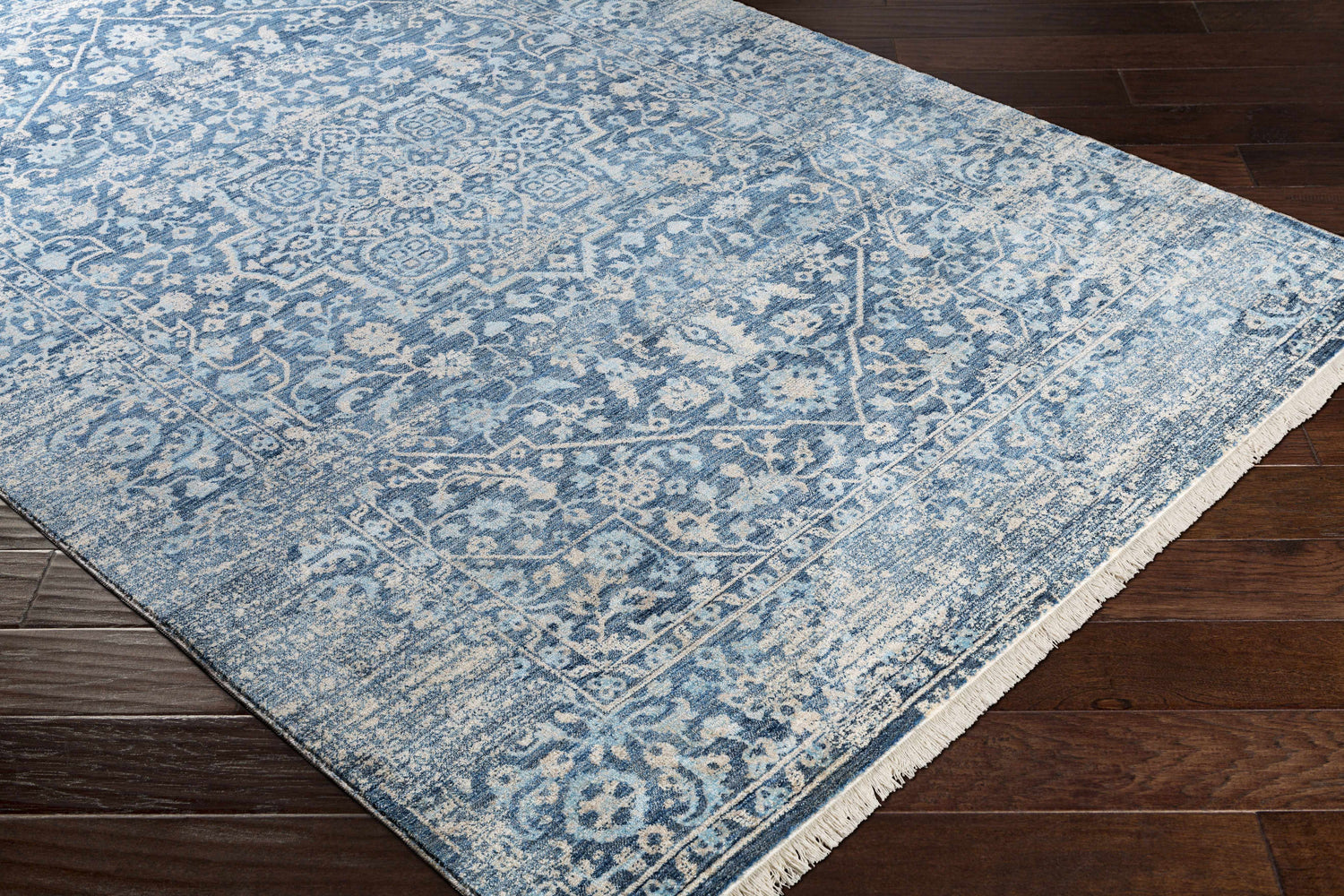Close-up of the Yorkana Distressed Blue Rug showing its traditional, vintage pattern and soft blue, beige, and gray colors. Corner