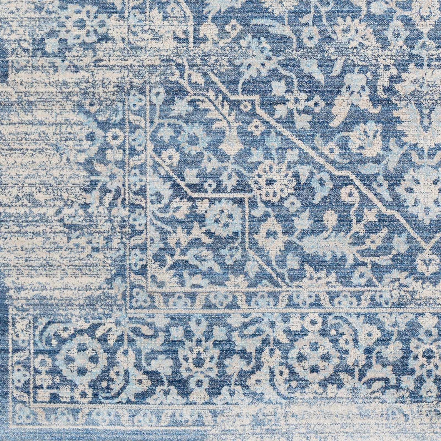 Close-up of the Yorkana Distressed Blue Rug, showcasing its traditional floral pattern and distressed texture in blue and beige. Swatch