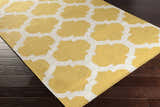 Close-up of the Youngtown Area Carpet. Hand-woven wool rug with a mustard yellow and ivory quatrefoil pattern. Corner