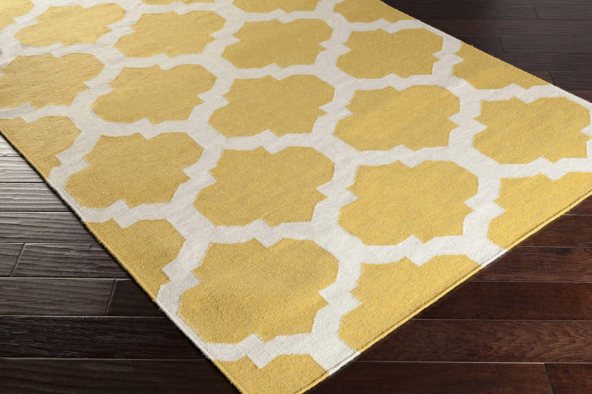 Close-up of the Youngtown Area Carpet. Hand-woven wool rug with a mustard yellow and ivory quatrefoil pattern. Corner
