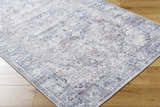 Close-up of the Yoshi Washable Area Rug in denim, cream, and gray with a traditional, distressed pattern on wood floor. Corner