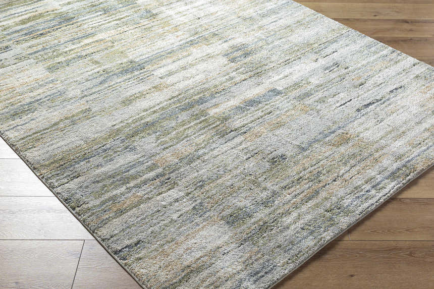 Close-up of the Yancy Thick Luxe Rug. Beige, gray, olive, and tan tones create a contemporary linear pattern. Corner