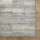 Close up of the Yancy Thick Luxe Rug showing beige, gray, olive, and tan horizontal stripes on a textured surface. Corner