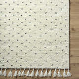 Close-up of the hand woven Yuuna Area Rug. Pearl wool rug with black dot pattern and tassels. Farmhouse style. Swatch
