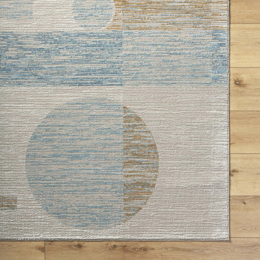 Close up of the Yoite Area Rug showing blue, ivory, and mustard geometric pattern on a textured polyester rug. Corner