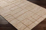 Close-up of the hand woven Zana Area Rug. Tan, brown, and off-white jute rug with a contemporary geometric pattern. Corner
