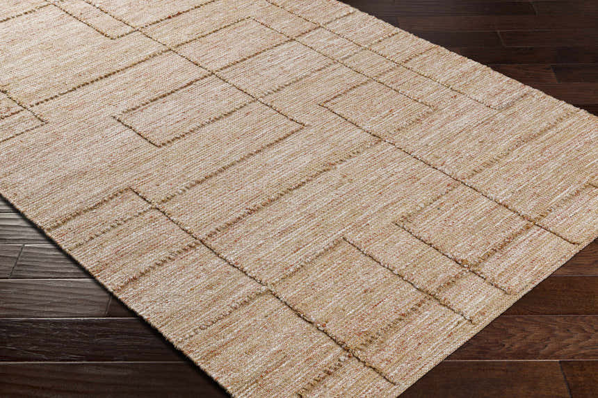 Close-up of the hand woven Zana Area Rug. Tan, brown, and off-white jute rug with a contemporary geometric pattern. Corner