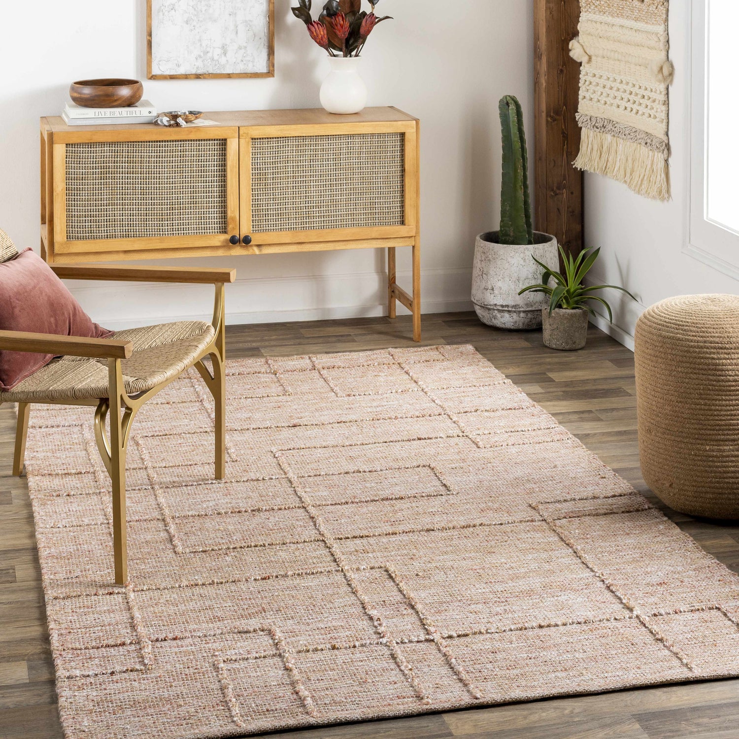Living room scene with a tan Zana Area Rug, woven chair, and mid-century modern cabinet. Neutral colors and natural textures create a calming mood. Roomscene-Rectangle