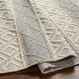 Close-up of Zaza Wool Rug in bone and cloud gray. Hand-woven geometric pattern with textured details. Fold