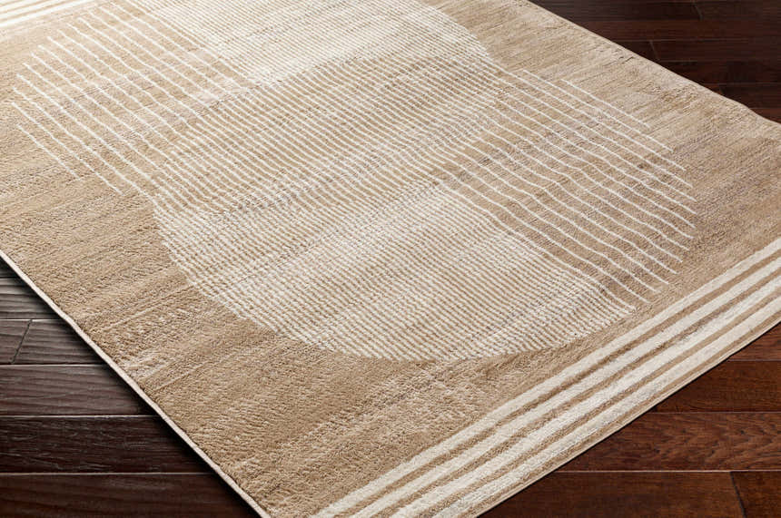 Close-up of the Zeke Area Rug in bone and mocha, featuring a geometric pattern with parallel lines on dark wood flooring. Corner