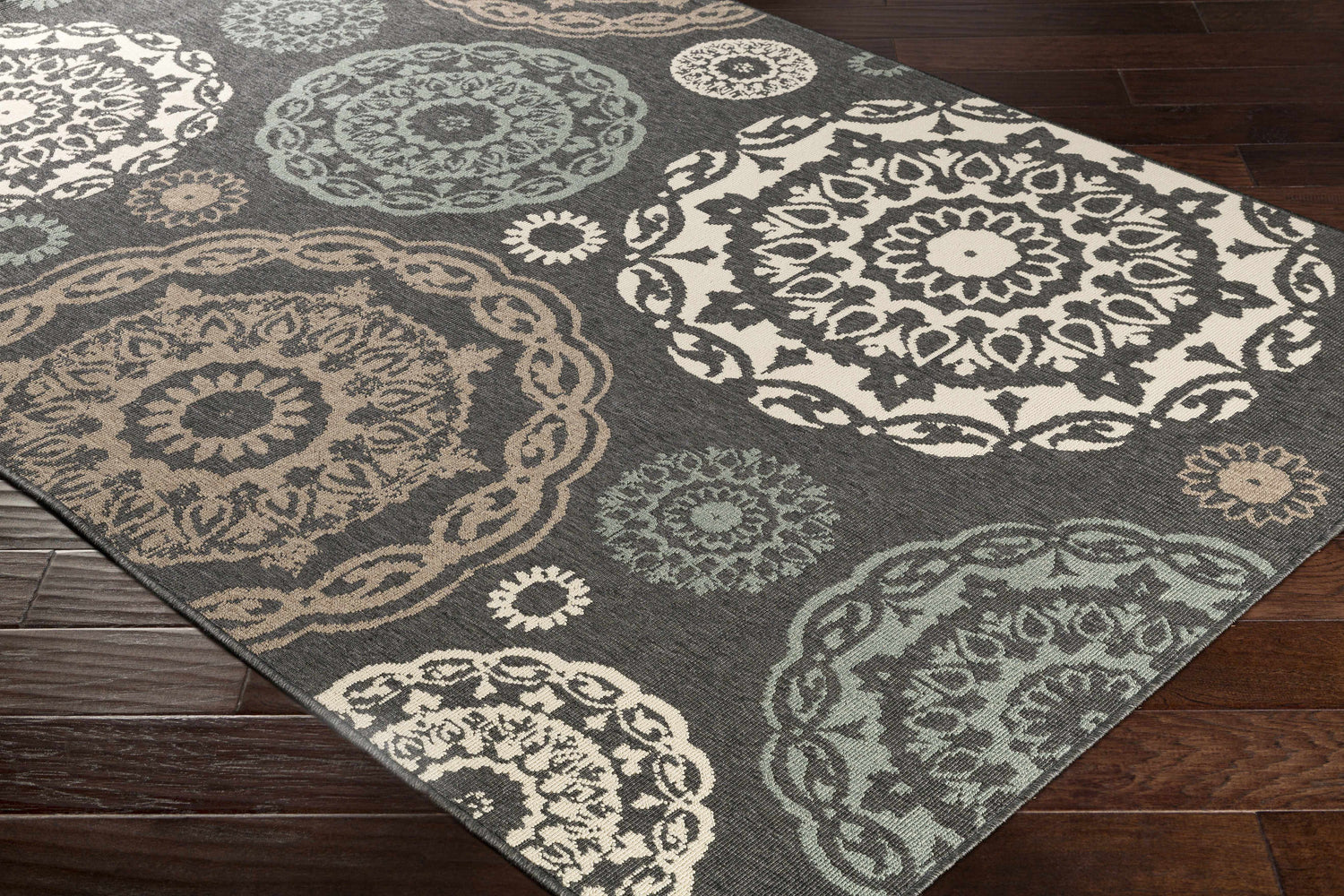 Close-up of Zephyrhills Area Rug showing beige, black, brown, dark red, and sage floral medallion pattern. Corner