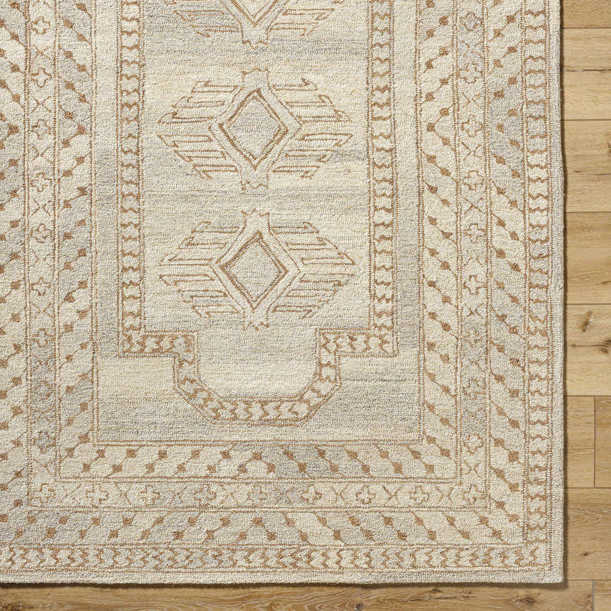 Close-up of the hand-tufted Zlata Area Rug. Farmhouse style with geometric brick red and tan pattern on pearl wool. Corner