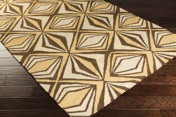 Close-up of Zieglerville Area Carpet. Wool rug with geometric pattern in dark brown, mustard, peach, tan, and wheat on dark wood floor. Corner