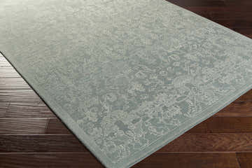 Close-up of the hand-knotted Zillah Area Carpet. Farmhouse style rug in light blue wool with traditional patterns. Corner