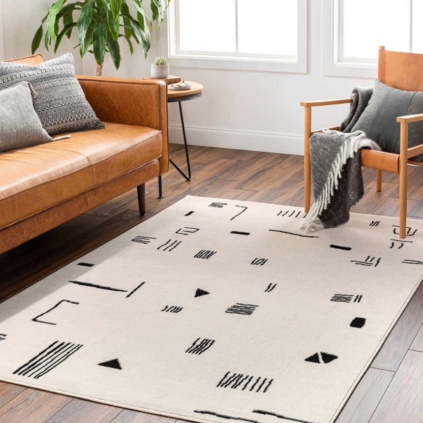 Living room with brown leather sofa and Zale Area Rug in bone with dark gray geometric design. Roomscene-Rectangle