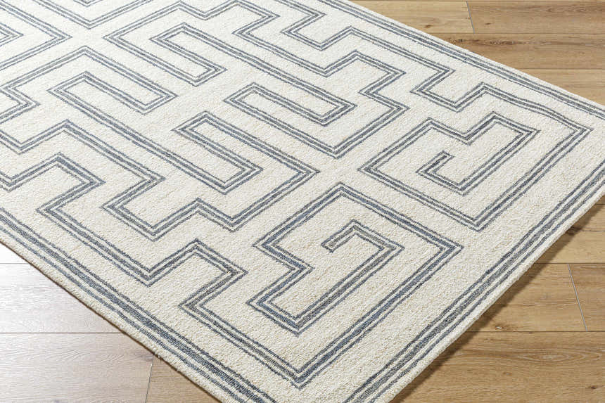 Close-up of the hand-tufted Zhang Area Rug. Gray geometric maze pattern on a light silver 100% wool rug. Farmhouse style. Corner