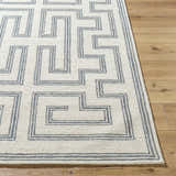 Close-up of the hand-tufted Zhang Area Rug, showcasing its gray geometric pattern on a light silver wool texture. Front