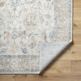 Close-up of the Uriel Thick Luxe Rug showing its beige, gray, and tan traditional floral pattern and machine-woven construction. Fold