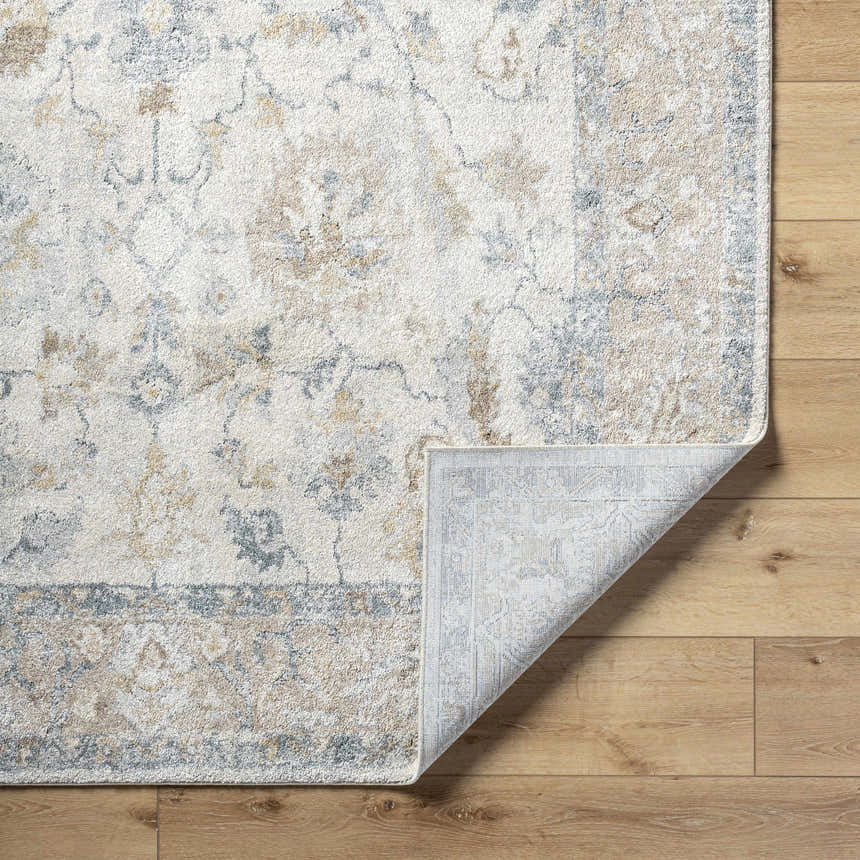 Close-up of the Uriel Thick Luxe Rug showing its beige, gray, and tan traditional floral pattern and machine-woven construction. Fold