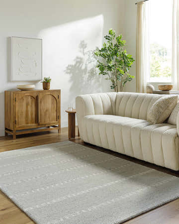 Living room scene with a cream sofa and ash Zelda Area Rug, light wood accents, and natural light. Roomscene-Rectangle