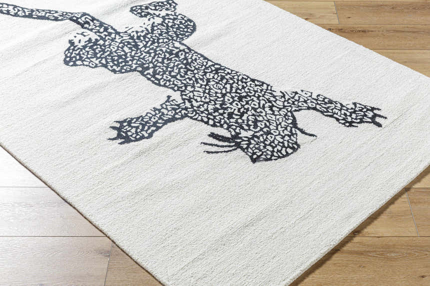 Close up of the Zosia Area Rug, a hand-tufted wool rug with a black leopard design on an off-white background. Corner